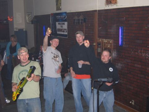 1977 Ford F-150 - People gather inside a dimly lit establishment, with one man holding an inflatable guitar.