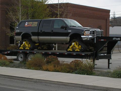 1990 Ford Bronco - This truck is equipped with tracks instead of wheels and is being transported on a trailer.