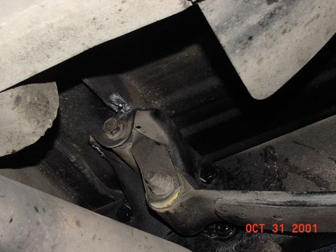 1990 Ford Bronco - A close-up view of a rusty metal bracket attached to the undercarriage of a vehicle.