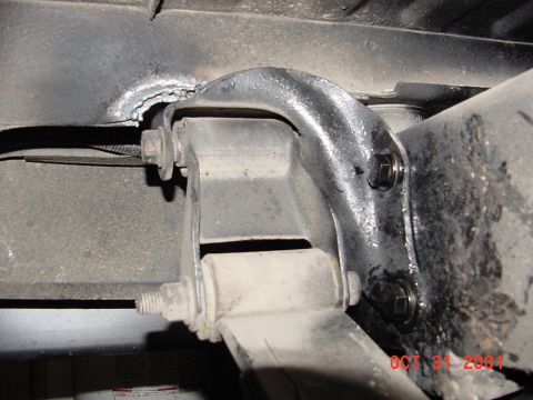 1990 Ford Bronco - A close-up view of a vehicle's undercarriage suspension system, showing welded metal and bolts.