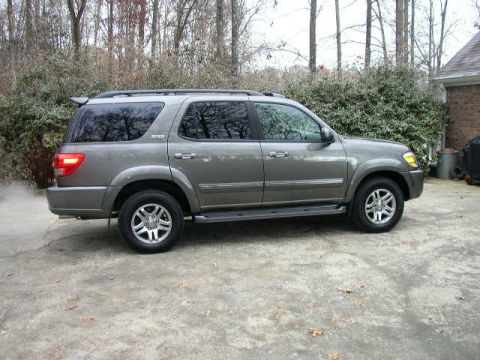 1995 Ford Bronco - This gray SUV is parked on a concrete surface with trees and a house in the background.