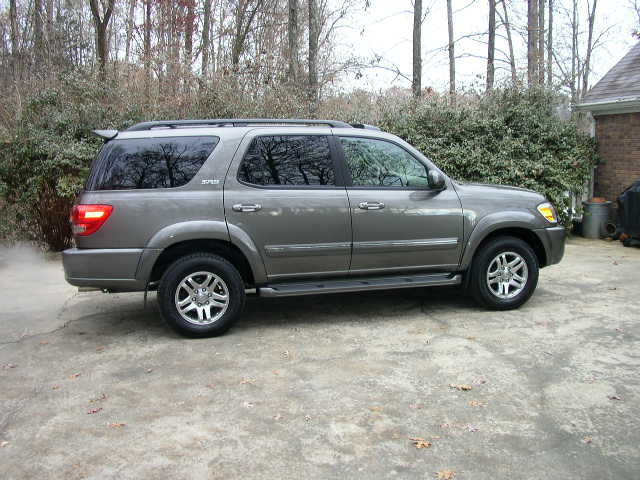 Gray SUV parked on concrete, side view. Visible spoiler, roof rack, and alloy wheels