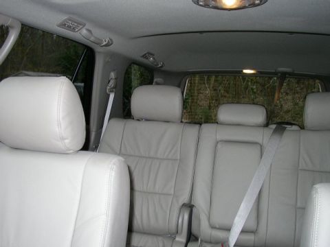 1995 Ford Bronco - The interior of a vehicle shows the rear seating area with light gray leather seats and seatbelts.