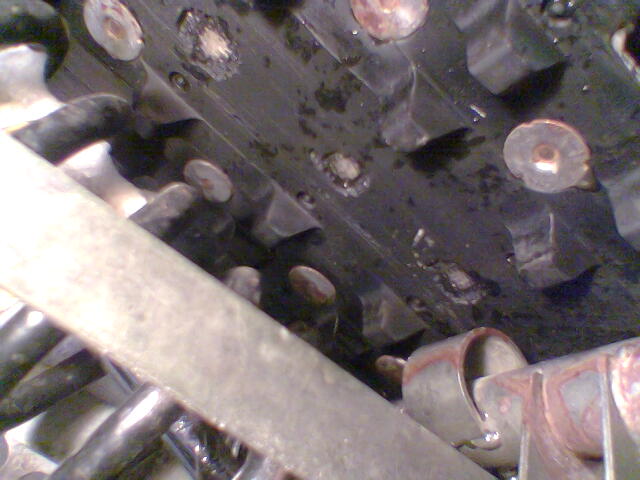 Close-up of greasy studded mechanical component with metal brackets