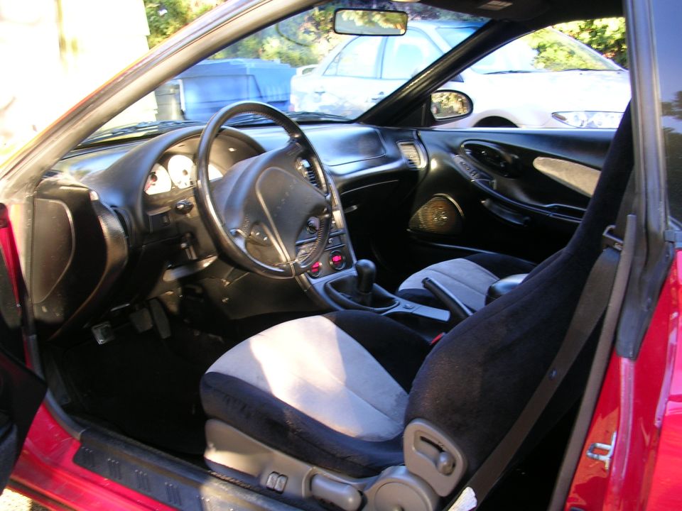 Interior view of a red car showing dashboard, steering wheel, and seats