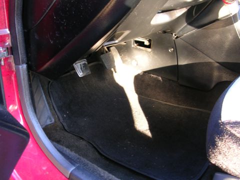 1996 Ford Probe - The interior footwell of a red car, showing the pedals and carpeted floor.