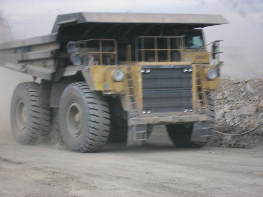 Front view of a yellow mining dump truck on a dirt road