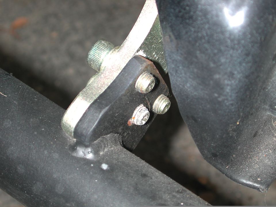 Close-up of a metal bracket with three screws on a black pipe