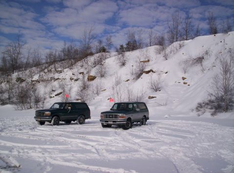 1996 Ford Bronco - Two 1996 Ford Broncos are parked in a snowy area with a hill behind them.