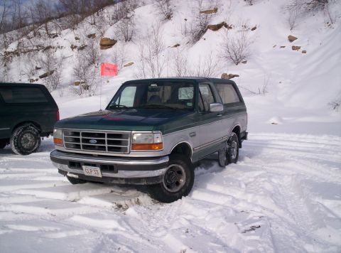1996 Ford Bronco - A two-tone Ford Bronco is parked in a snowy area with a second vehicle visible behind it.