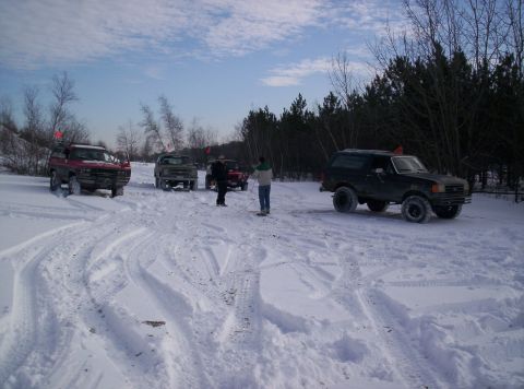 1996 Ford Bronco - Several vehicles are parked in a snowy area with trees in the background.