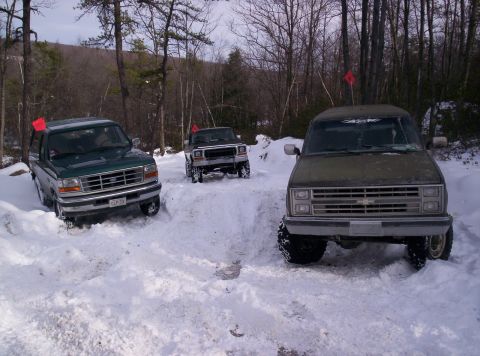 1996 Ford Bronco - Three SUVs navigate a snowy trail, with a green Ford Bronco in the foreground.