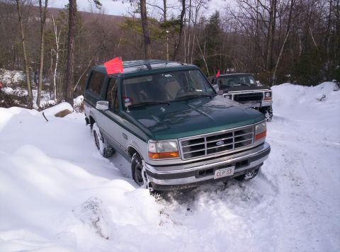 1996 Ford Bronco - A green and silver Ford Bronco navigates a snowy terrain with another vehicle behind it.