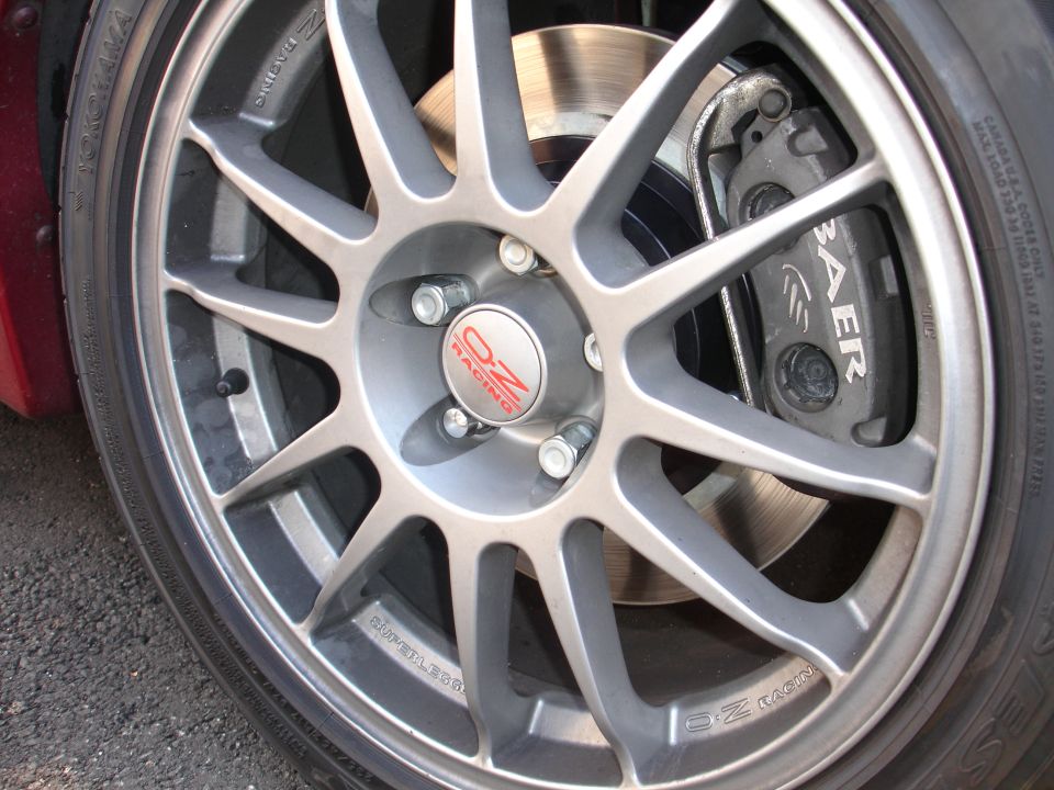 Close-up of a silver OZ Racing wheel with a red and silver center cap and a Baer brake caliper