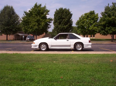 1992 Ford Bronco - White coupe parked on asphalt with grass in foreground and trees in background.