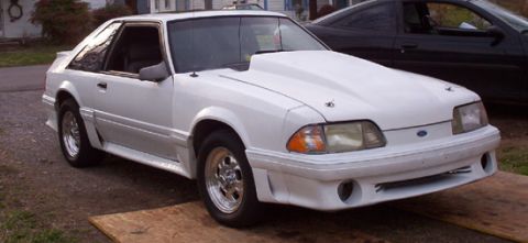1992 Ford Bronco - A white Ford Mustang with a prominent hood scoop is parked on wooden planks.