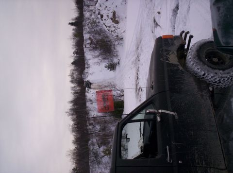 1996 Ford Bronco - A dark SUV is parked in a snowy area next to a red tarp.