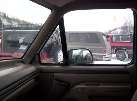 1996 Ford Bronco - View from inside a vehicle shows several SUVs parked in a snowy outdoor setting.