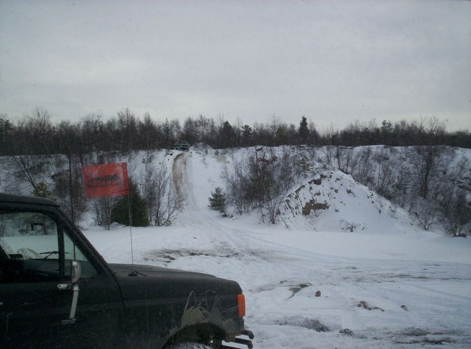 Dark Ford Bronco in snow, front quarter view. Red flag with text visible