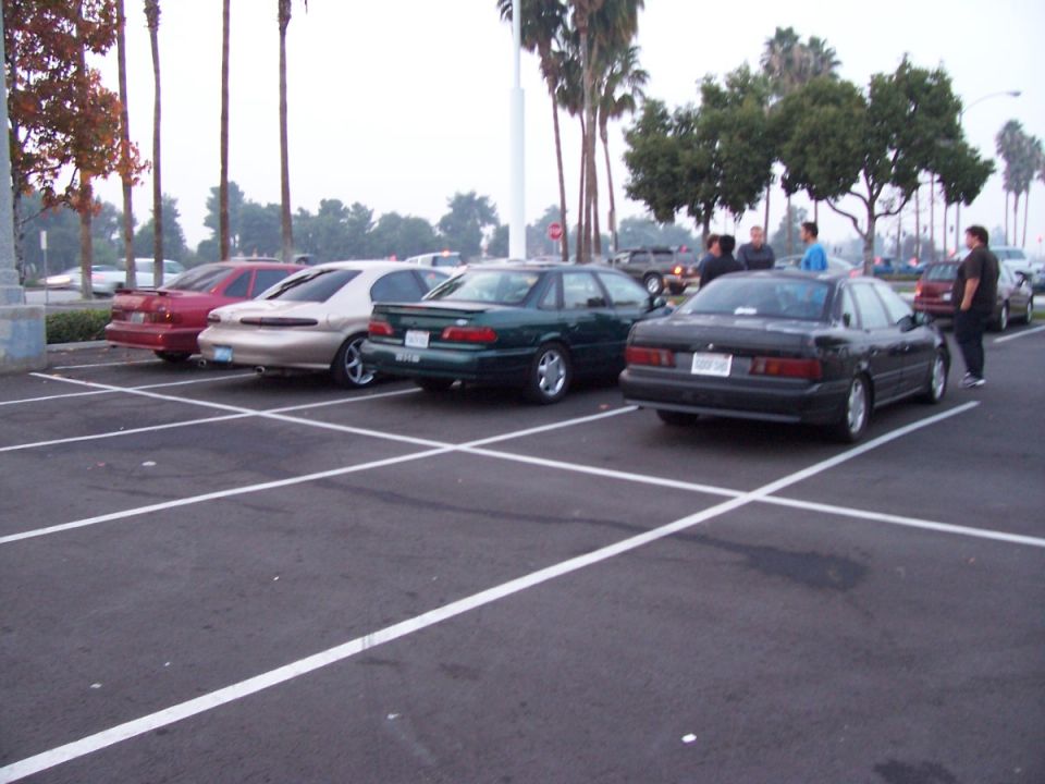 Four sedans parked in a lot, three in a row and one to the right