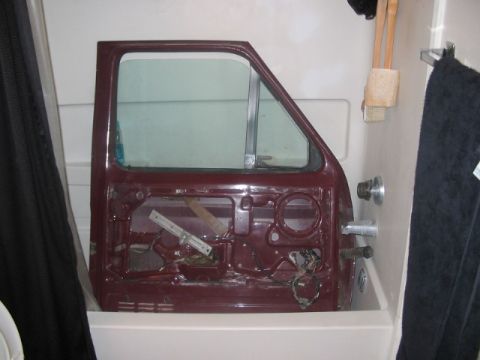 1991 Ford Bronco - A detached car door, likely for a Ford Bronco, is placed inside a bathtub.