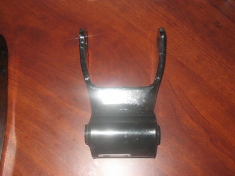 1991 Ford Bronco - A black metal leaf spring shackle, likely for a truck or SUV, is shown against a wooden background.