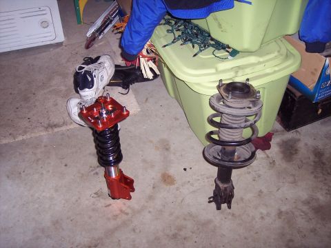 1995 Ford Probe - Car suspension parts are laid out on a concrete floor next to storage bins.