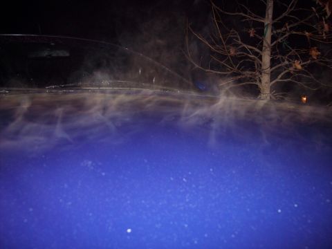 1995 Ford Probe - Steam rises from a blue car's hood on a cold night, obscuring the view of the windshield and a nearby tree.
