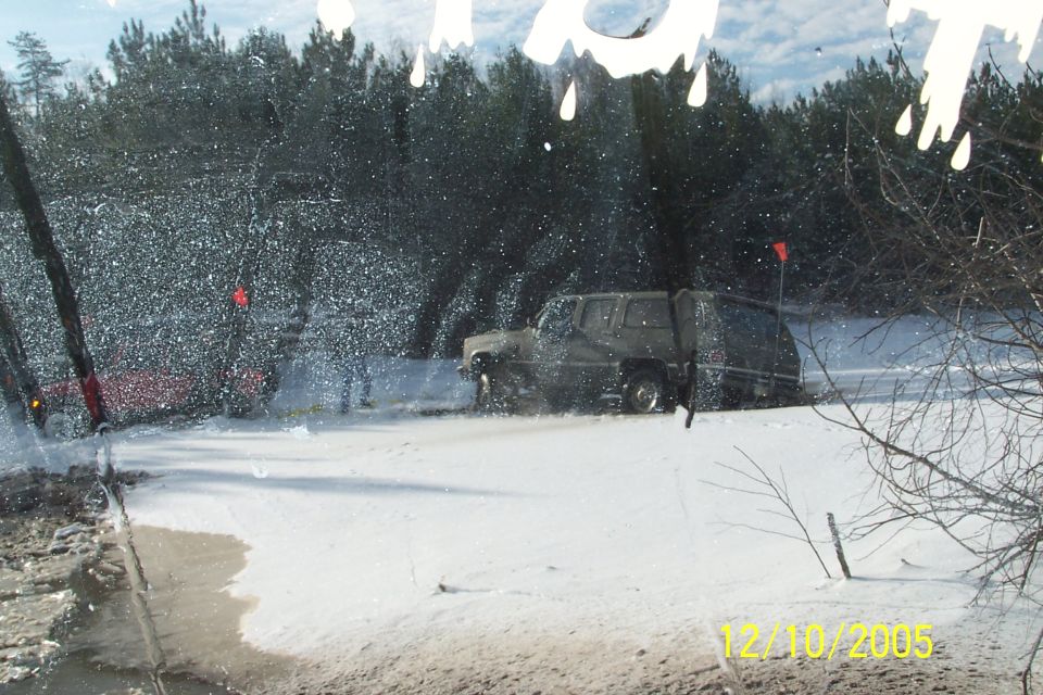 Off-road vehicle driving through snow with another vehicle partially visible behind it