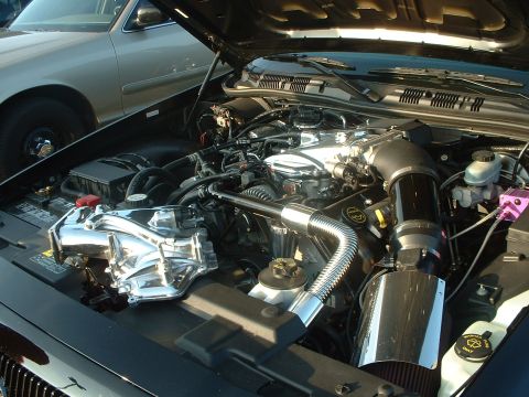 1999 Ford Crown Victoria - Customized engine bay a polished chrome intake system and aftermarket air filter, with another vehicle partially visible.