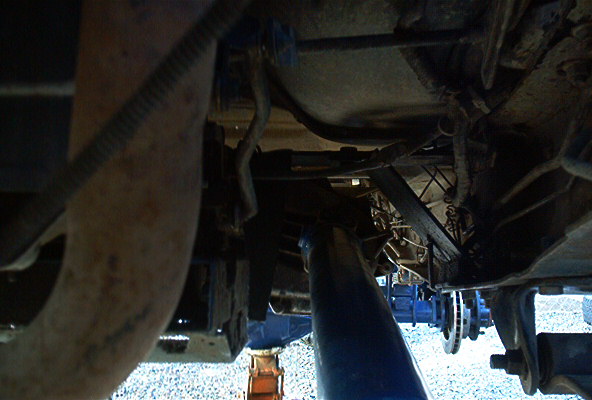 Underside view of a vehicle's transmission and exhaust system, possibly during maintenance