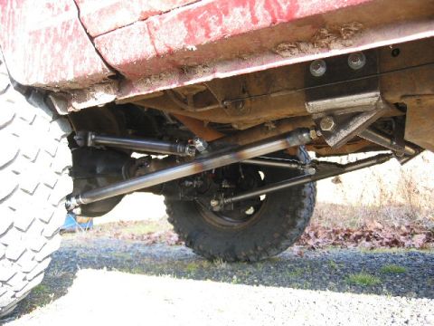 1991 Ford Explorer - Underbody shot of a lifted red truck/SUV showing freshly rebuilt front steering: new heavy-duty tie rod and drag link with adjustable sleev…