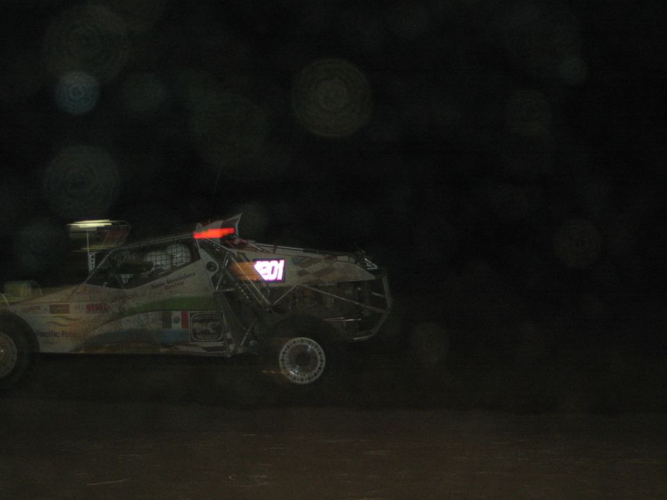 Off-road race buggy numbered 101 in profile on a very dark desert course at night