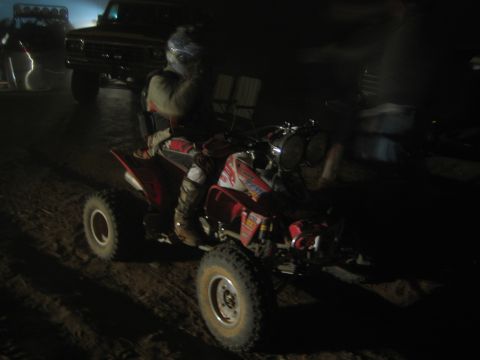 1990 Ford Bronco - helmeted rider on a red quad ATV at night, an older pickup truck visible in the background.