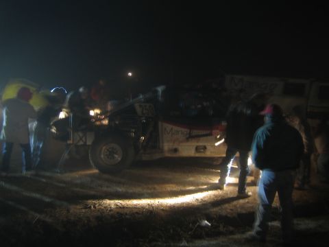 1990 Ford Bronco - crowd gathers around a number-250 off-road race truck illuminated against the dark desert night.