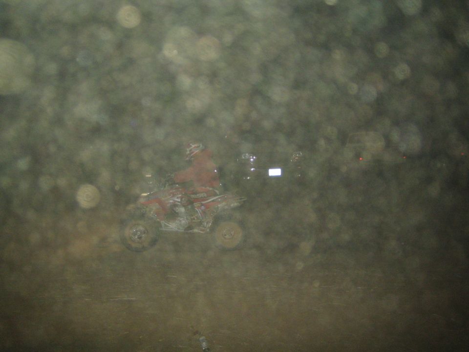 Distant red quad ATV at night seen through a dirty spotted lens