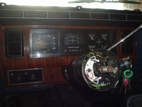 1984 Ford Bronco - Interior view of a vehicle's dashboard and exposed steering column, showing gauges and woodgrain trim.