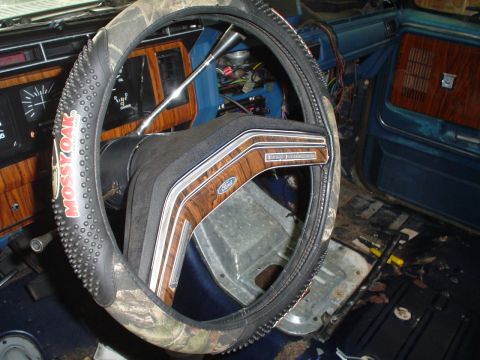 1984 Ford Bronco - The interior of a 1984 Ford Bronco shows wood grain trim and a camouflage steering wheel cover.