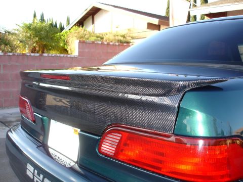 1993 Ford Taurus - Carbon fiber spoiler installed on the trunk of a green sedan, with aftermarket taillights visible.