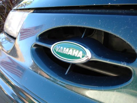 1993 Ford Taurus - Yamaha emblem on a dark green vehicle grille with an American flag reflection on the headlight.