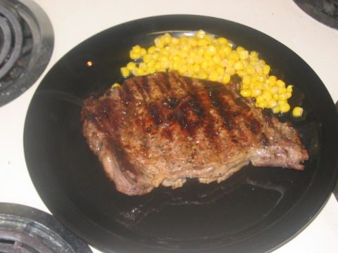 1991 Ford Bronco - A grilled steak with corn is served on a black plate, placed on a stovetop.