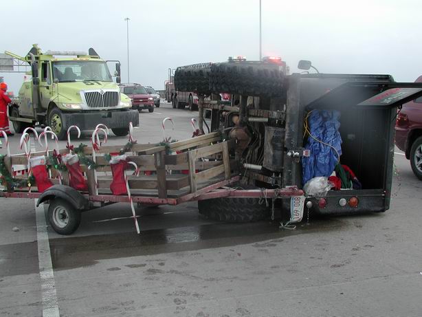 Trailer decorated with stockings and candy canes, next to a utility truck and other vehicles