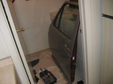 1991 Ford Bronco - A single car door is stored indoors, leaning against a washing machine.