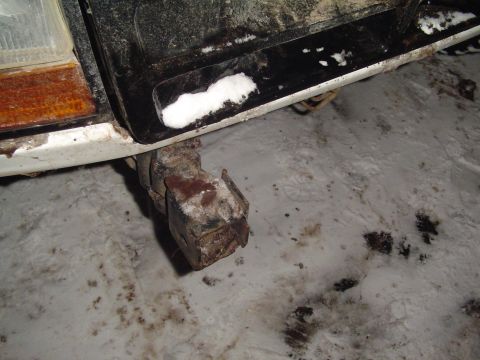 1994 Ford Bronco - A close-up view of a vehicle's undercarriage, showing a rusty component and snow on the ground.