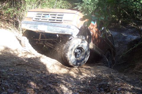 1987 Ford Bronco - This 1987 Ford Bronco tackles a challenging off-road course, its front wheel deep in mud.