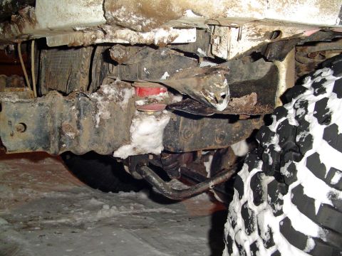 1994 Ford Bronco - Close-up of a vehicle's undercarriage and tire, partially covered in snow.