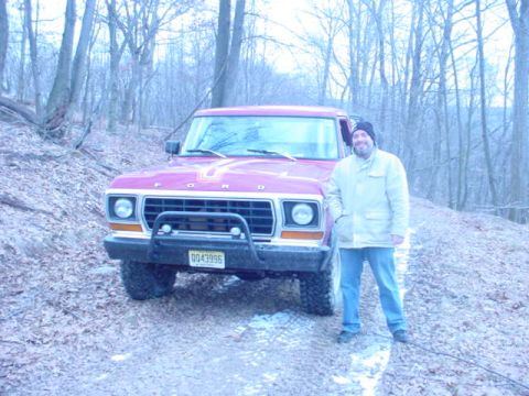 1979 Ford Bronco - A man stands next to a red 1978 Ford Bronco in a snowy, wooded environment.