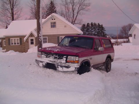 1994 Ford Bronco - A two-tone Ford Bronco is partially buried in snowdrifts on a winter day.