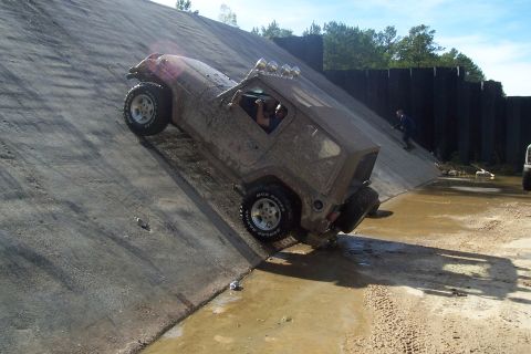 1987 Ford Bronco - A Jeep is shown climbing a steep, wet concrete surface, possibly during an off-road event.