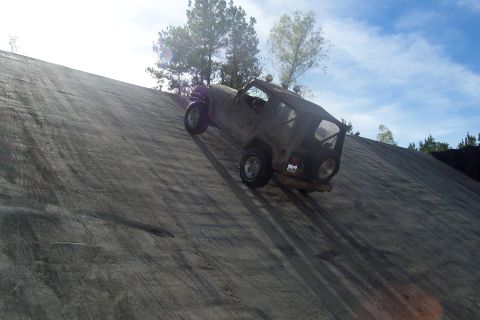 1987 Ford Bronco - A Jeep Wrangler is shown ascending a steep, textured incline under a bright sky.